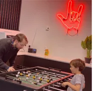 A game of foosball in the RUBIX office under the neon sign